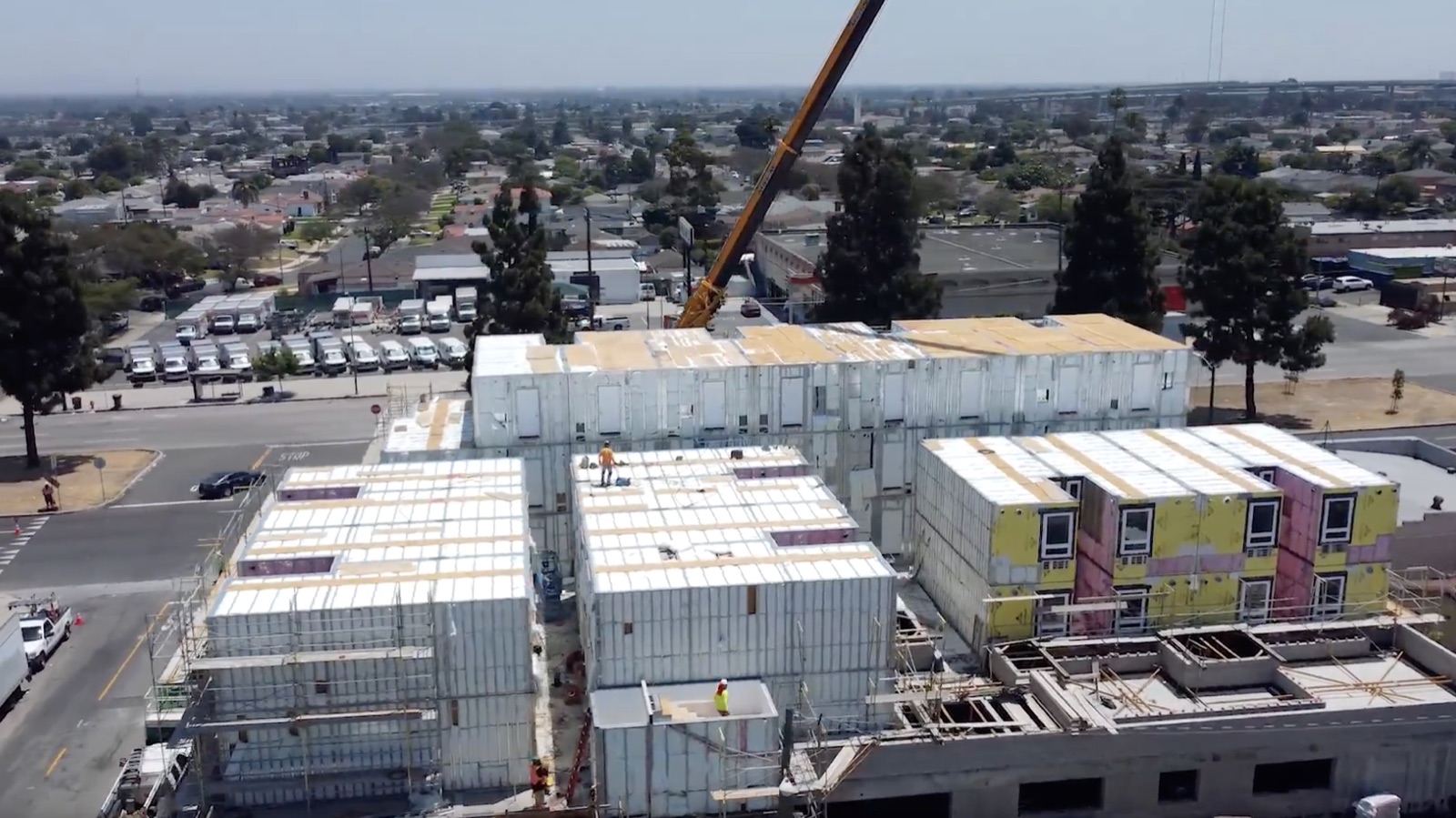 A tower crane lifting a finished volumetric module into place